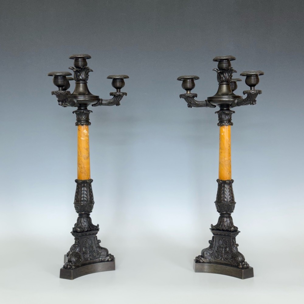 A pair of French Restoration period dark bronze candelabra with four candle branches each, supported by cylindrical yellow marble columns on detailed cast bronze tripartite bases. View VII