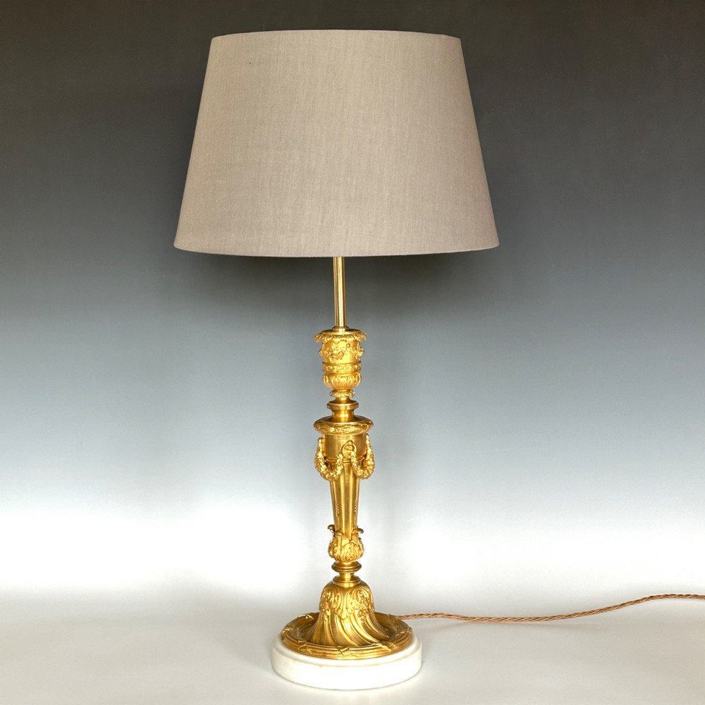 A Louis XV style gilt bronze ormolu table lamp featuring cast foliage swags, acanthus leaf detailing, and a circular white marble base. View II