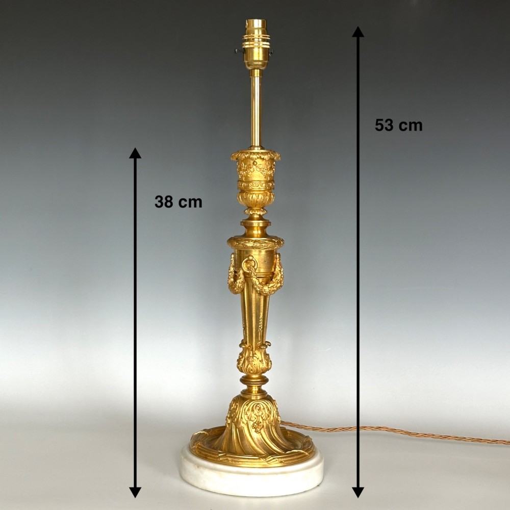 A Louis XV style gilt bronze ormolu table lamp featuring cast foliage swags, acanthus leaf detailing, and a circular white marble base. View IV
