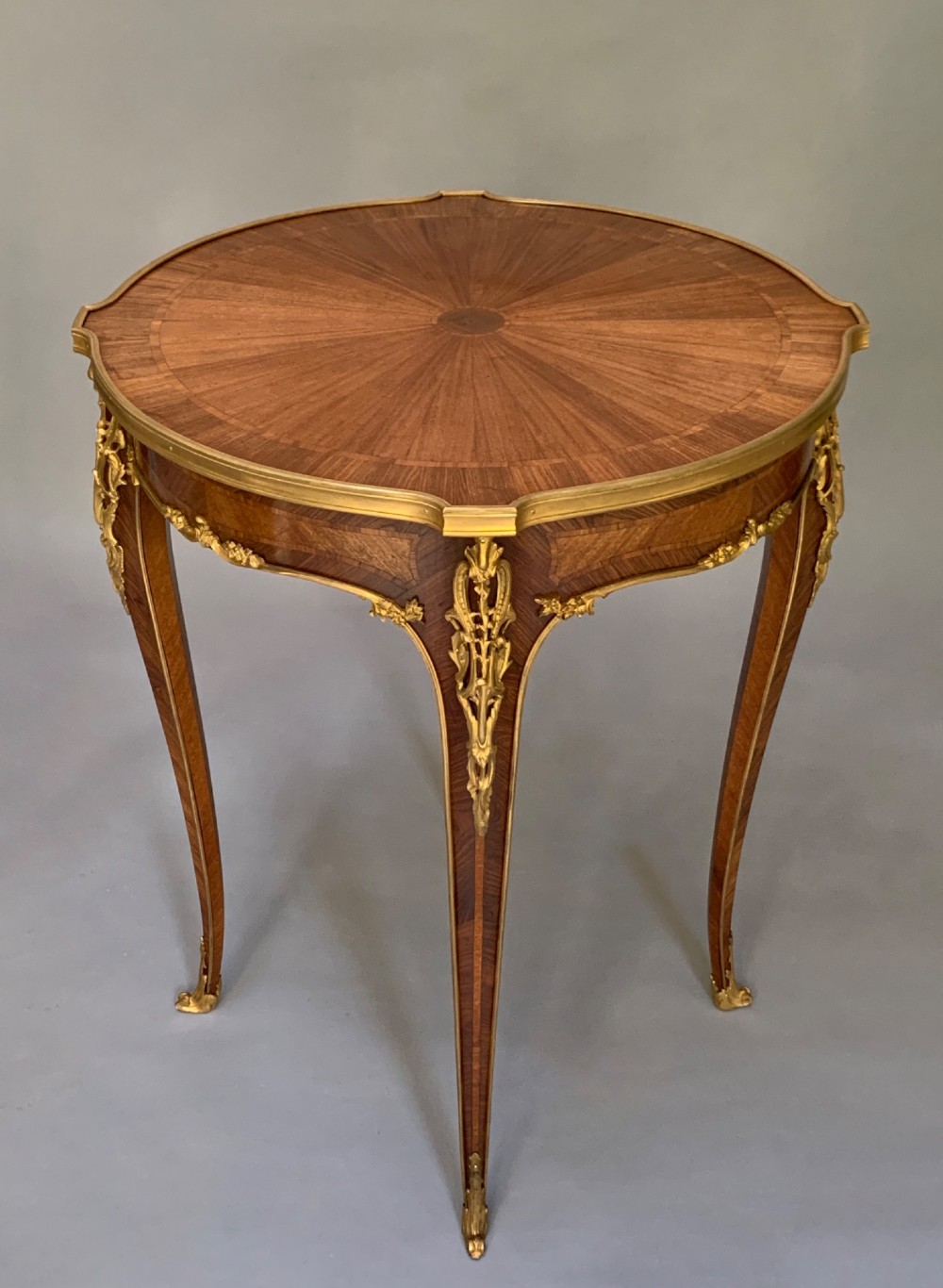 A nineteenth-century French kingwood occasional table featuring quarter-veneered parquetry, slender cabriole legs, and decorative gilt-bronze mounts. View X