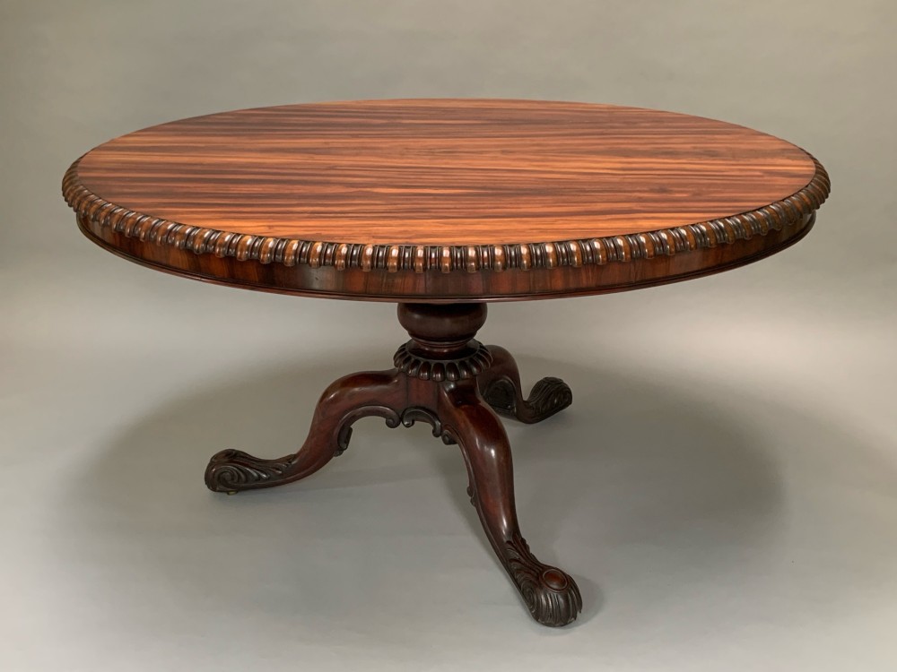 A 19th-century William IV oval centre table constructed from figured albuera wood with a gadrooned rim and a turned pedestal base.
