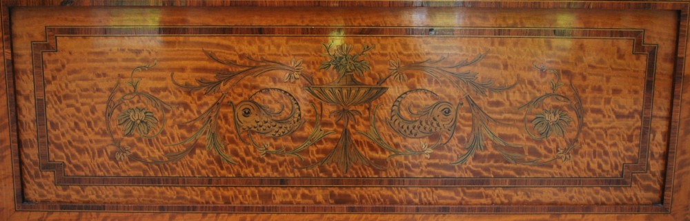 A late Victorian satinwood display cabinet featuring three glazed doors, detailed marquetry inlay, fabric-lined interior shelves, and splayed legs. View VI