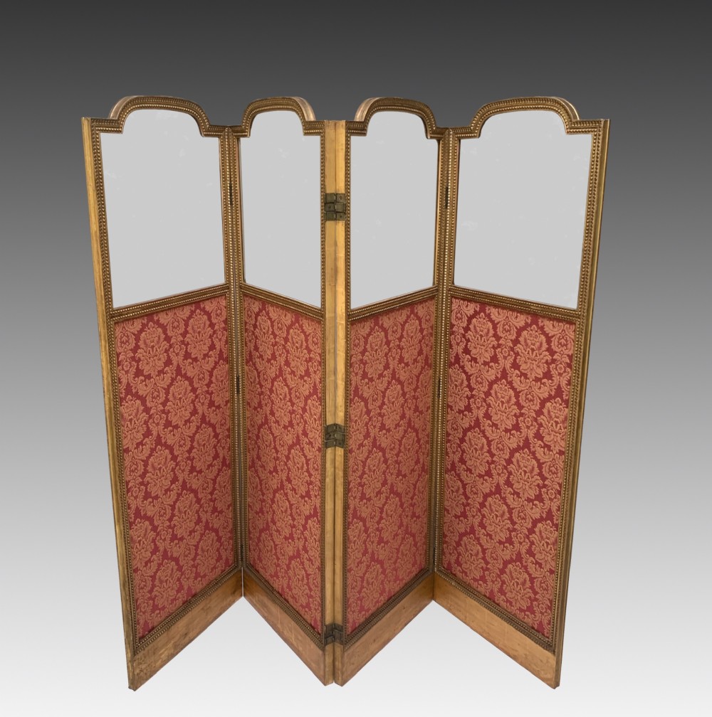 A Victorian four-fold screen featuring carved giltwood frames with arched tops, upper neutral panels, lower red and gold damask fabric panels, and brass hinges. View II