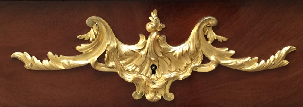 A French Louis XV style bureau plat crafted from dark polished wood with serpentine cabriole legs, elaborate gilt-bronze ormolu mounts, and a black leather writing top. View V