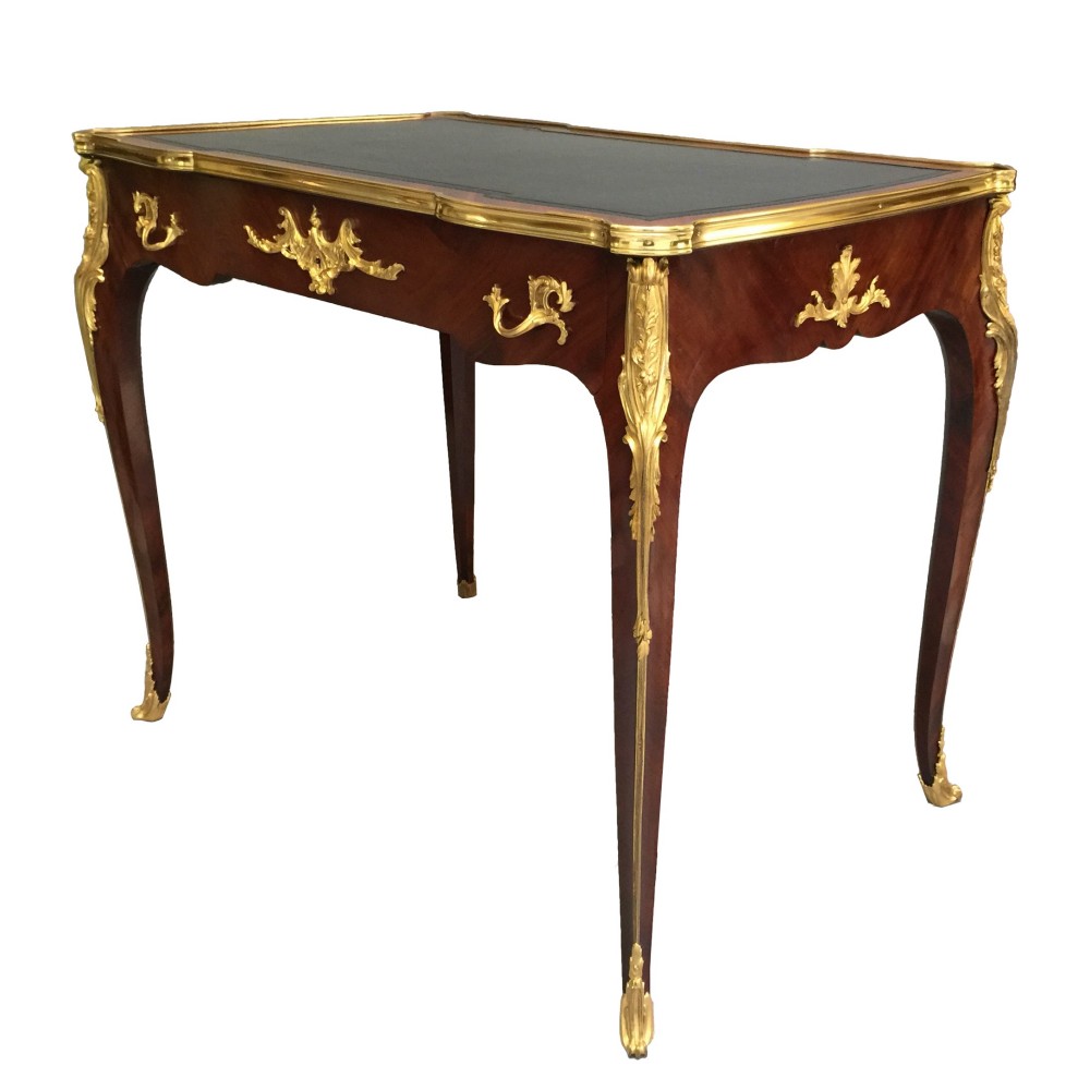 A French Louis XV style bureau plat crafted from dark polished wood with serpentine cabriole legs, elaborate gilt-bronze ormolu mounts, and a black leather writing top. View VII
