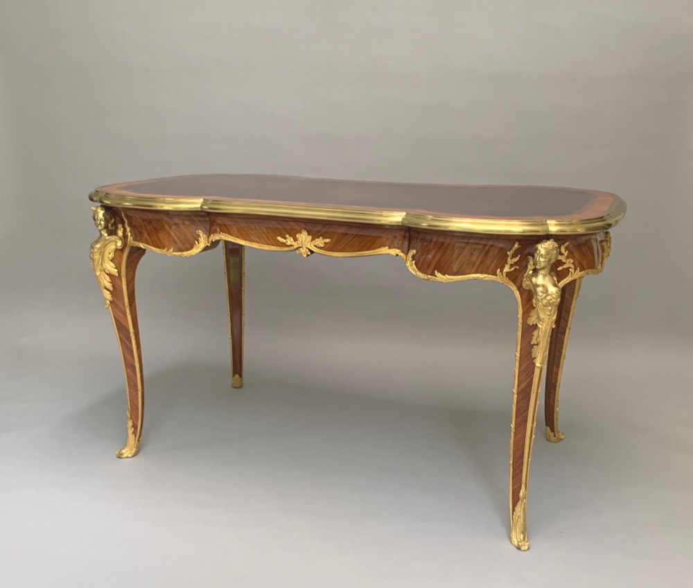 A French Louis XV style kingwood and rosewood centre table featuring serpentine edges, cabriole legs, and gilt-bronze mounts with female bust caryatids.