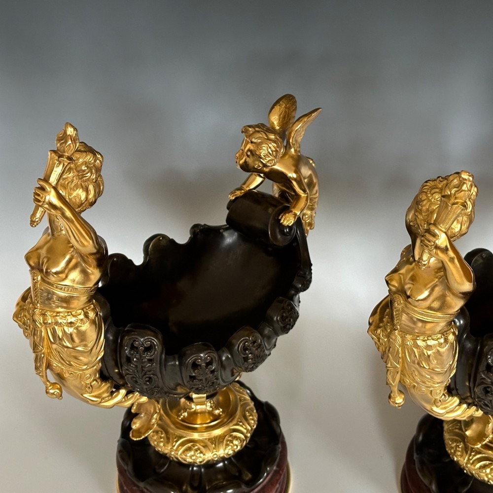 A pair of antique French gilt and patinated bronze centrepiece bowls mounted on red marble bases, decorated with sculpted cherubs and female figures holding torches. View VI