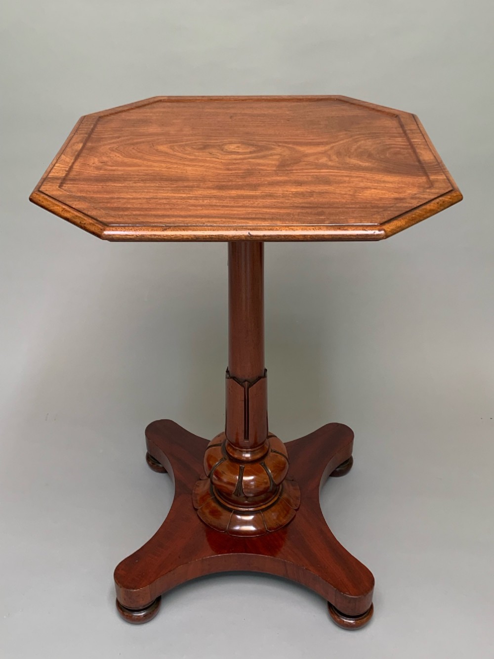 A Victorian mahogany side table with an octagonal top, turned pedestal stem, and carved quadripartite base.