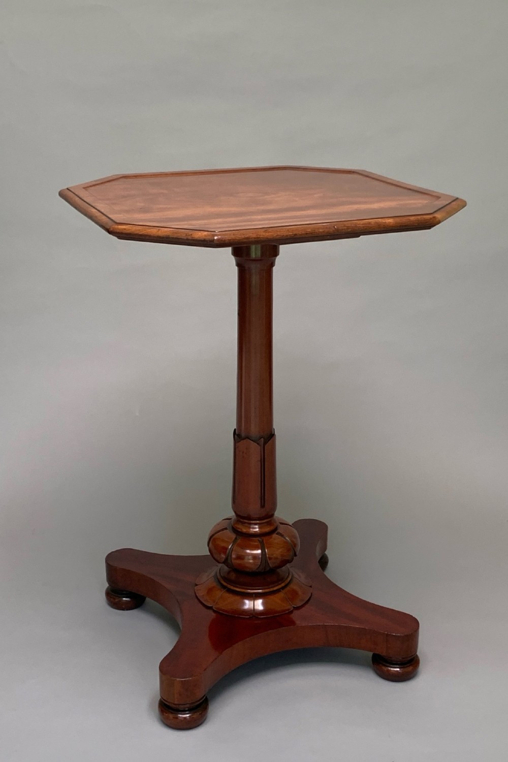 A Victorian mahogany side table with an octagonal top, turned pedestal stem, and carved quadripartite base. View III