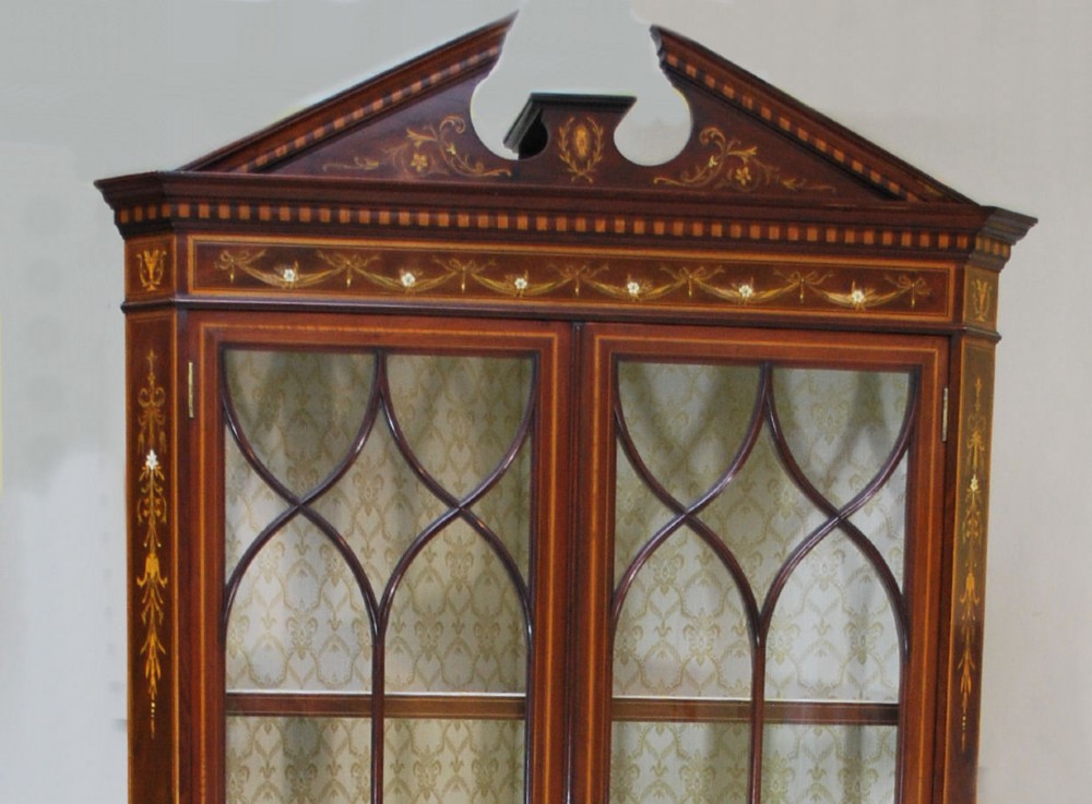 A late Victorian mahogany corner cabinet featuring intricate marquetry inlays of urns and foliage, glazed upper doors with curved glazing bars, and a swan neck pediment. View II