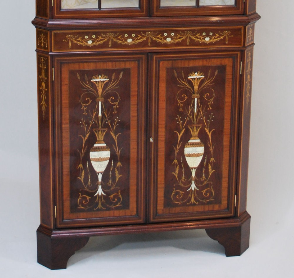 A late Victorian mahogany corner cabinet featuring intricate marquetry inlays of urns and foliage, glazed upper doors with curved glazing bars, and a swan neck pediment. View III
