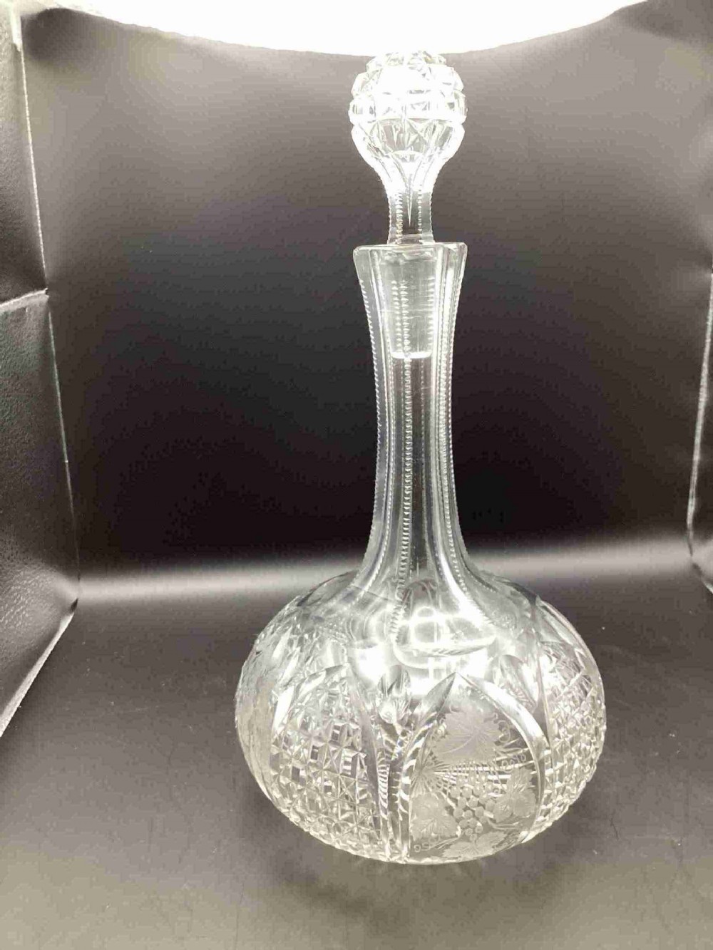 A Victorian clear cut glass sherry decanter with a bulbous body featuring geometric cuts, etched botanical motifs, a slender neck, and a faceted stopper.
