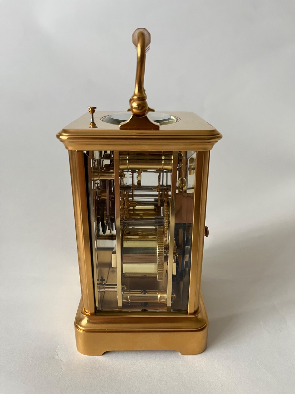 A rectangular gilt brass French repeating carriage clock with a top handle, glass side panels, and a white enamel dial with black Roman numerals. View III