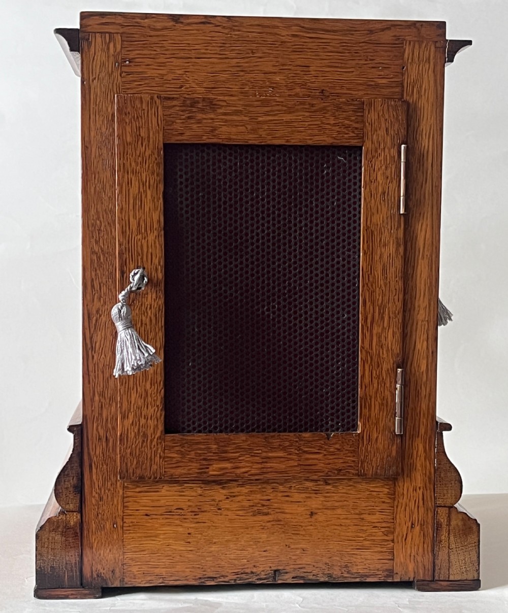 An antique Victorian oak library clock featuring a square silvered dial with Roman numerals and spandrel engravings set within a stepped wooden case. View II
