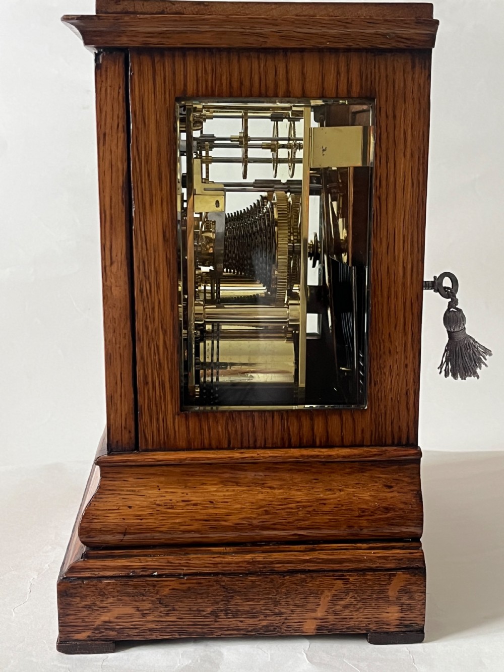 An antique Victorian oak library clock featuring a square silvered dial with Roman numerals and spandrel engravings set within a stepped wooden case. View III