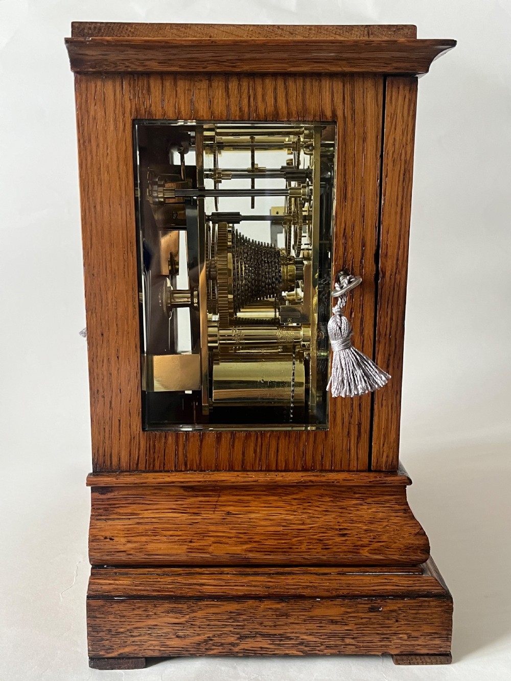 An antique Victorian oak library clock featuring a square silvered dial with Roman numerals and spandrel engravings set within a stepped wooden case. View IV
