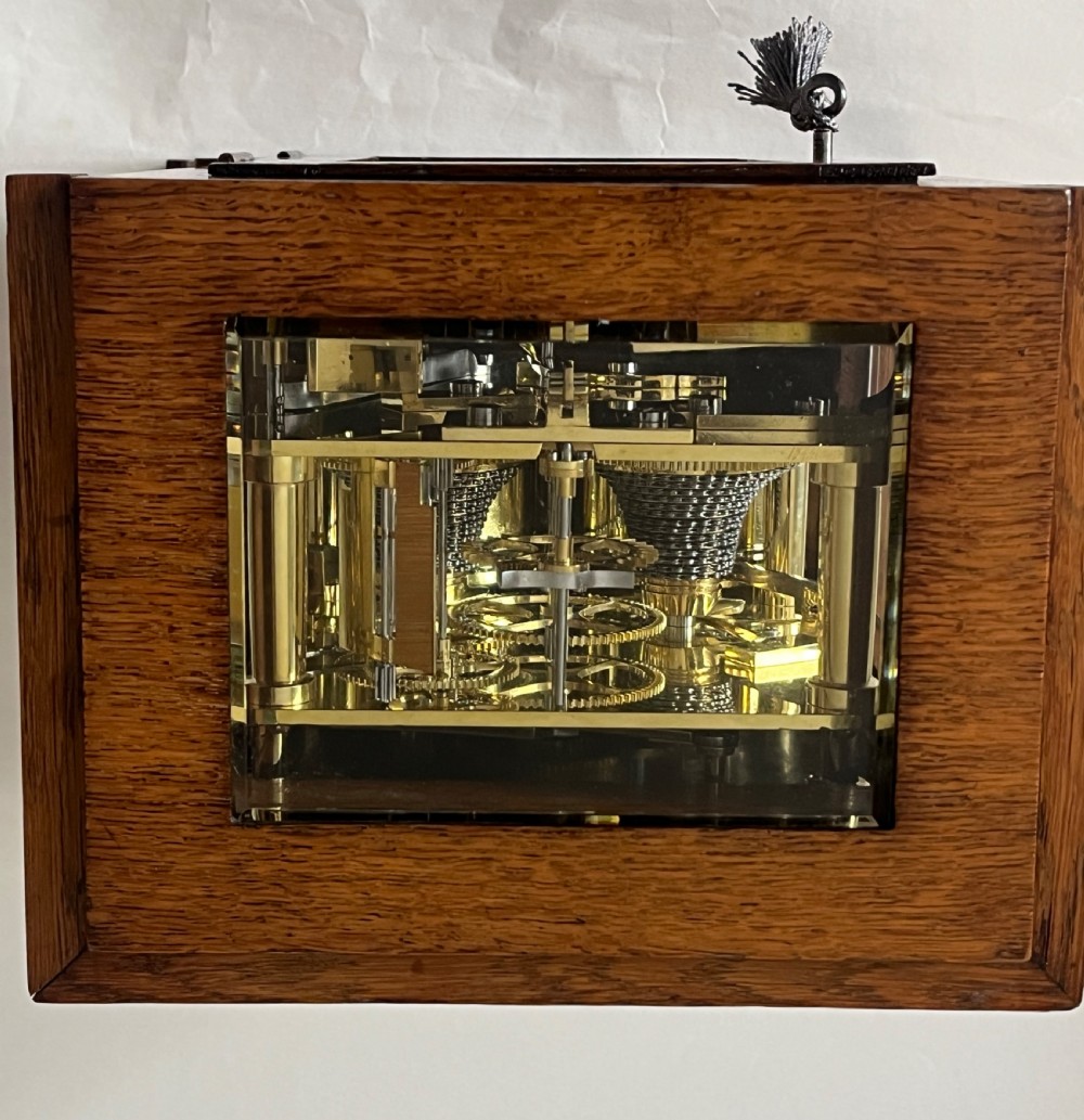 An antique Victorian oak library clock featuring a square silvered dial with Roman numerals and spandrel engravings set within a stepped wooden case. View VI
