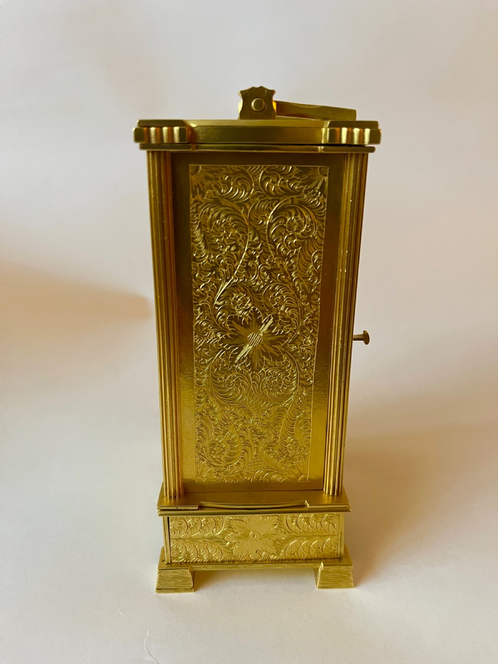 An engraved gilt brass Victorian English fusee carriage clock featuring Roman numerals and a folding carrying handle. View IV