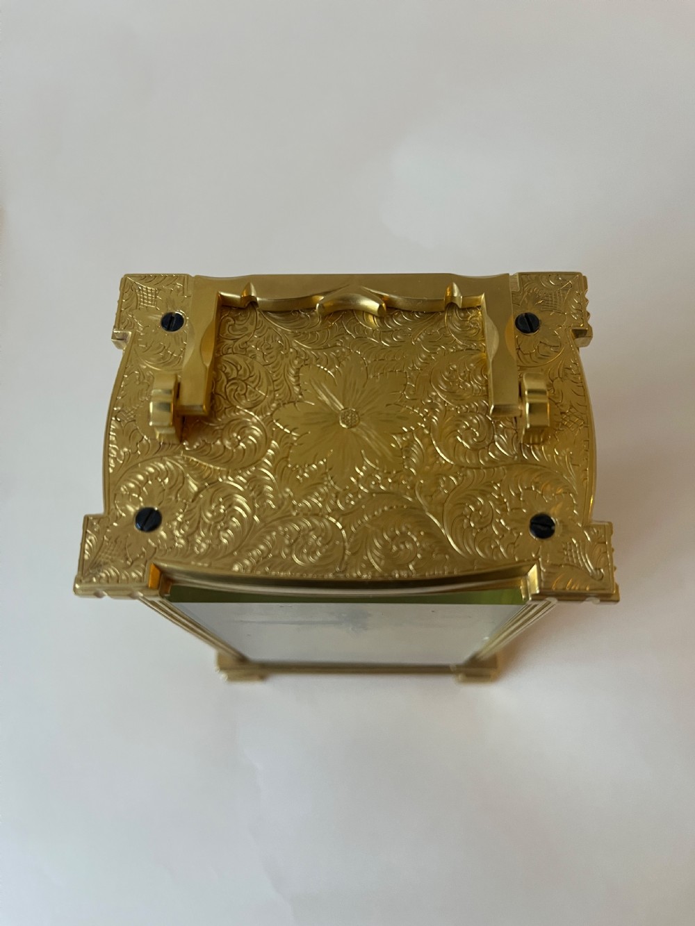 An engraved gilt brass Victorian English fusee carriage clock featuring Roman numerals and a folding carrying handle. View V