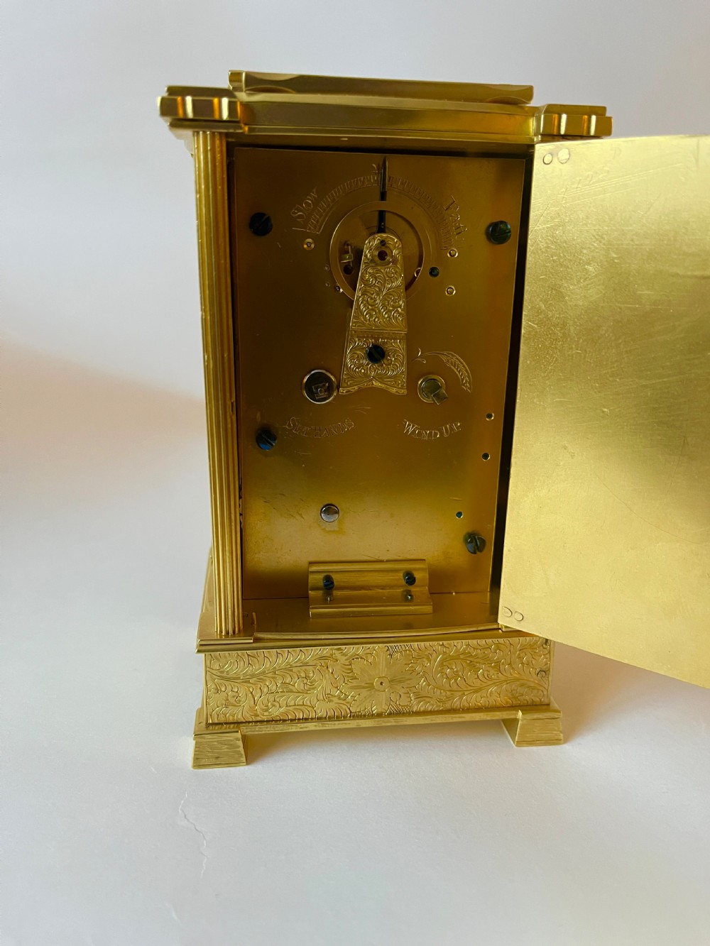 An engraved gilt brass Victorian English fusee carriage clock featuring Roman numerals and a folding carrying handle. View VI