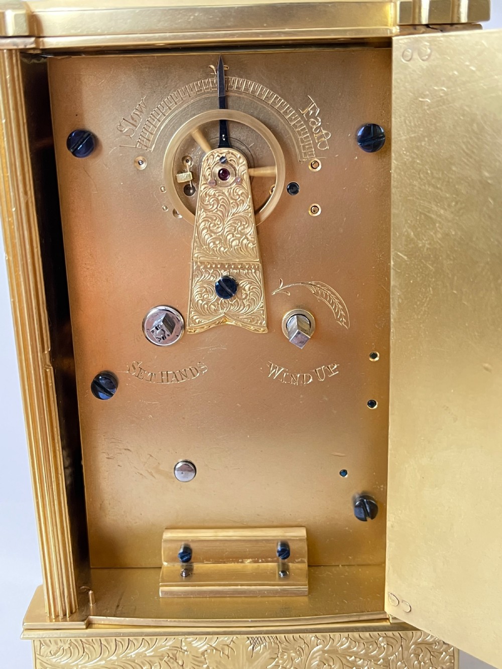 An engraved gilt brass Victorian English fusee carriage clock featuring Roman numerals and a folding carrying handle. View VII