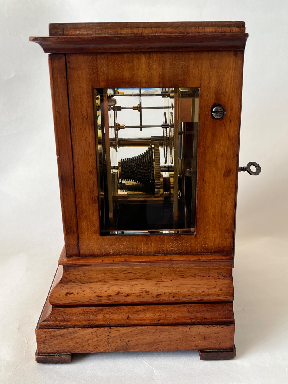 A Victorian mahogany library clock featuring a square timber case with a silvered engraved dial, black Roman numerals, and a key visible on the side. View IV
