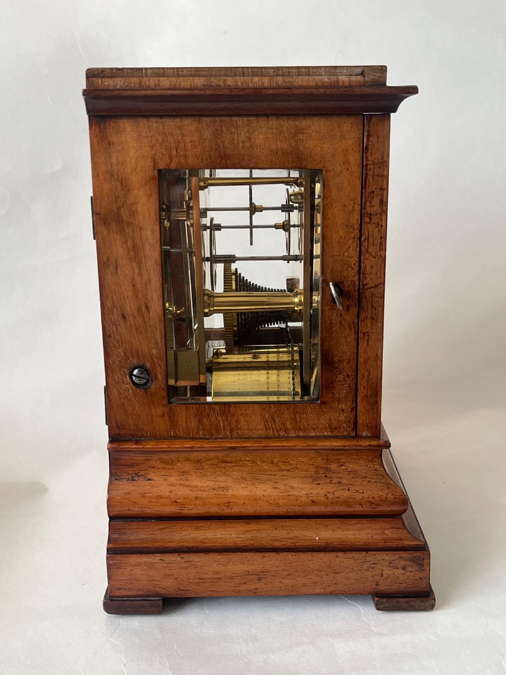 A Victorian mahogany library clock featuring a square timber case with a silvered engraved dial, black Roman numerals, and a key visible on the side. View V