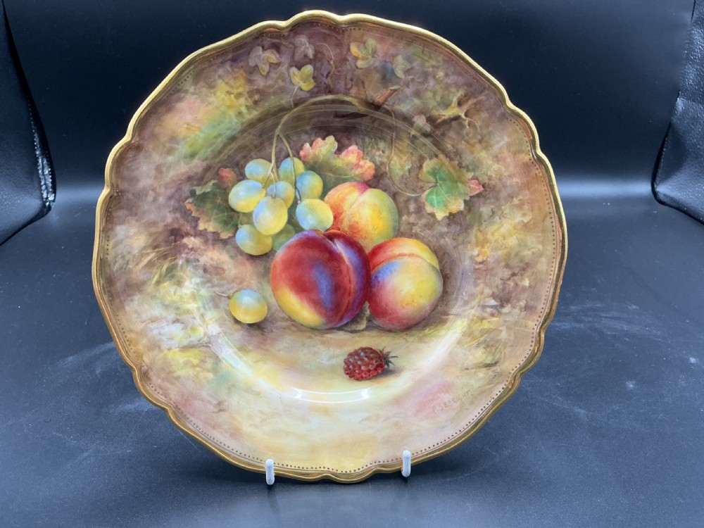 A circular hand-painted Royal Worcester porcelain cabinet plate depicting peaches and grapes with a gilded shaped rim.