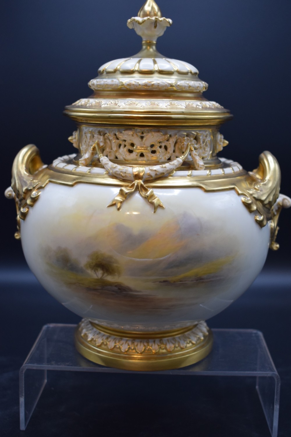 A gilded porcelain pot pourri vase with a pierced cover, twin scroll handles, and a painted landscape featuring Highland cattle. View II