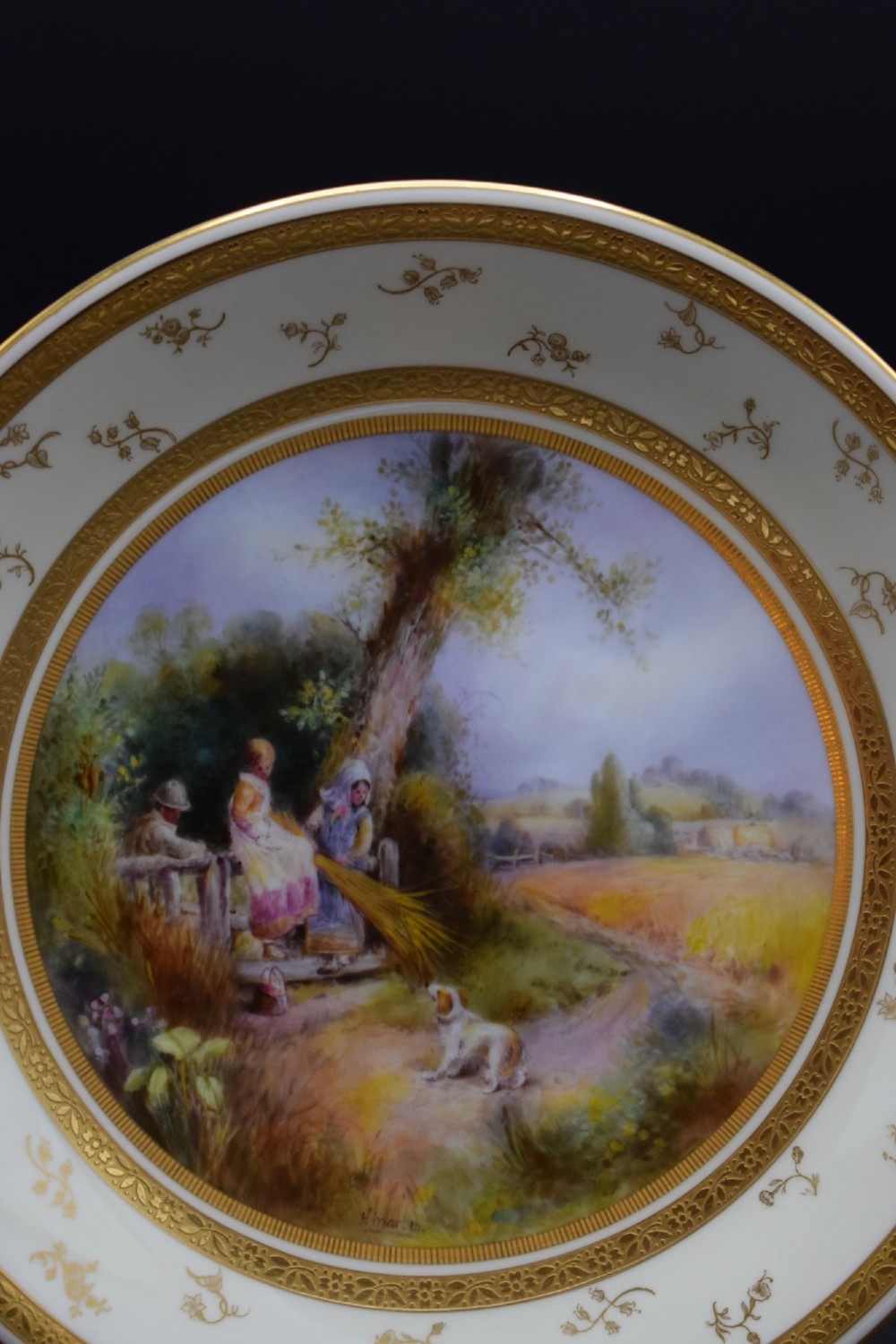 A pair of circular porcelain plates decorated with hand-painted pastoral landscapes and framed by wide cream borders with intricate gilded detailing. View III