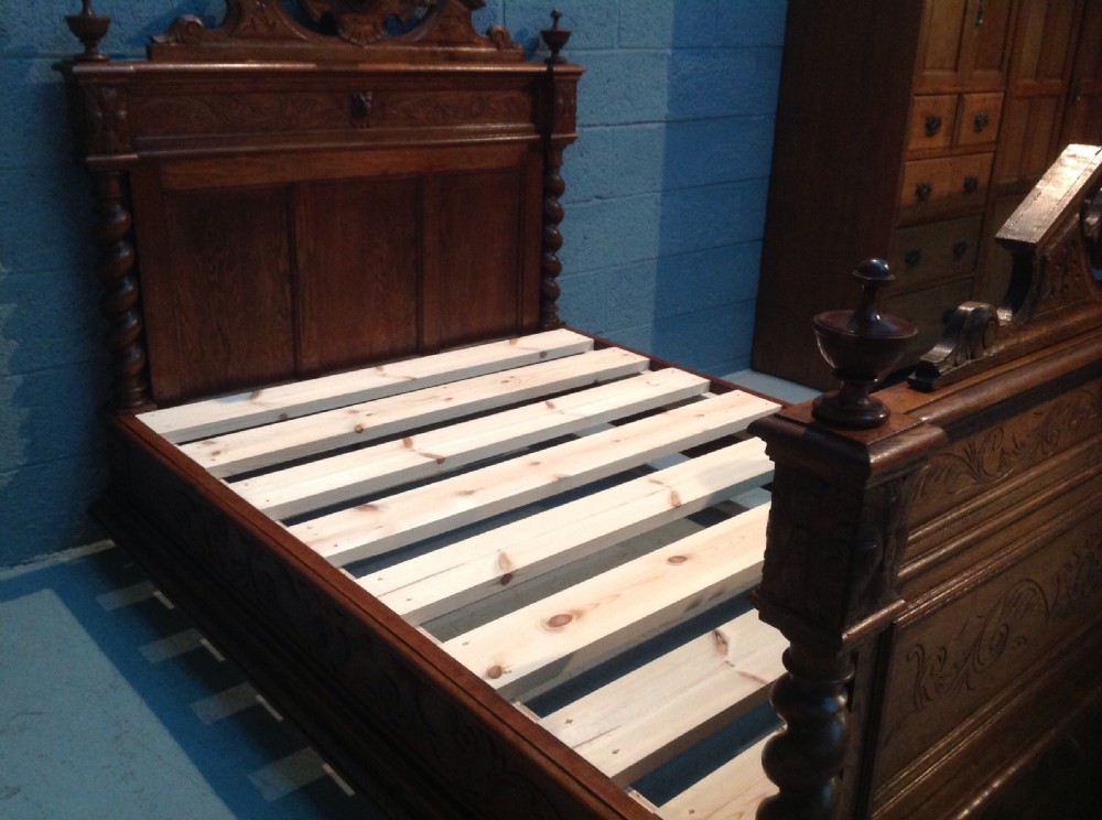 An antique French Breton oak double bed frame featuring intricate relief carvings, barley twist column accents, and decorative cresting on the headboard and footboard. View VIII