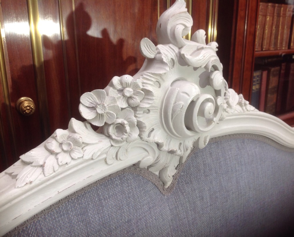 A French Louis XV style bed frame featuring an off-white painted carved timber surround encasing grey fabric upholstered headboard and footboard panels. View IV