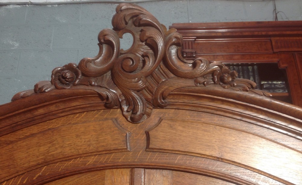 A tall French provincial carved oak armoire with two full-length mirrored doors, an arched cresting pediment, base drawers, and cabriole feet. View II