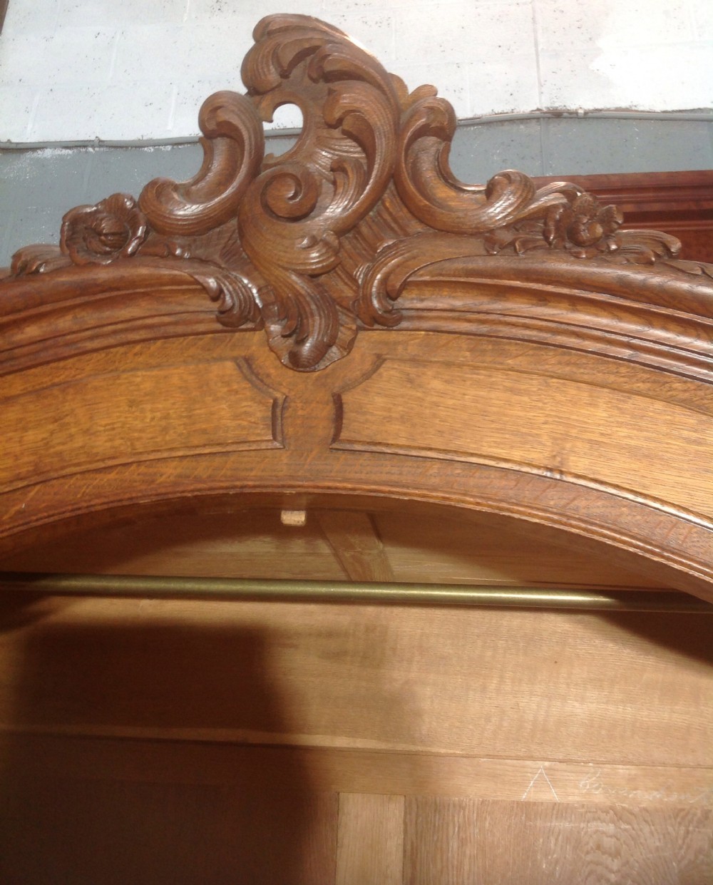 A tall French provincial carved oak armoire with two full-length mirrored doors, an arched cresting pediment, base drawers, and cabriole feet. View VII