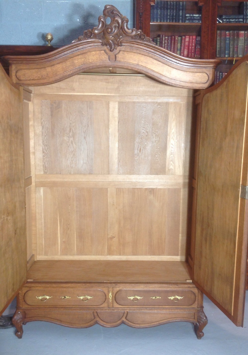 A tall French provincial carved oak armoire with two full-length mirrored doors, an arched cresting pediment, base drawers, and cabriole feet. View X