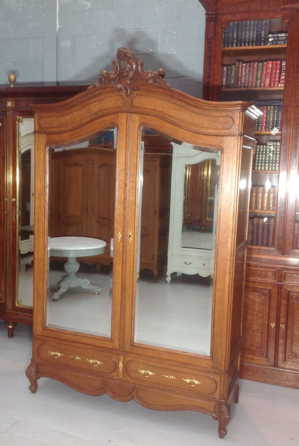 A tall French provincial carved oak armoire with two full-length mirrored doors, an arched cresting pediment, base drawers, and cabriole feet. View XI