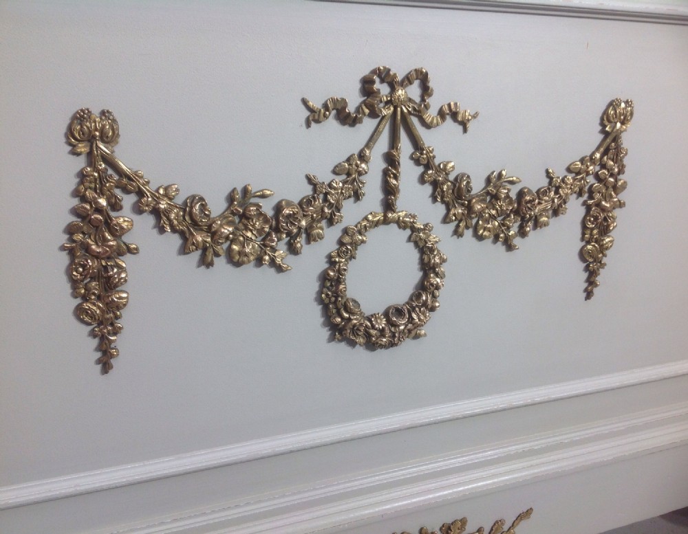An off-white painted French Neoclassical bed frame featuring a tall rectangular headboard, fluted turned legs, and intricate brass swag mounts on the footboard. View VII