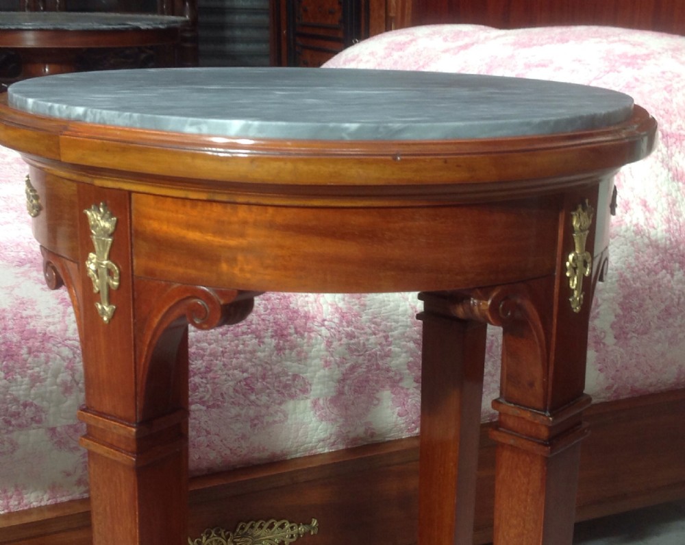 A pair of tall circular mahogany bedside tables featuring inset grey marble tops, gilt brass mounts, lower tier shelves, and brass claw feet. View IV