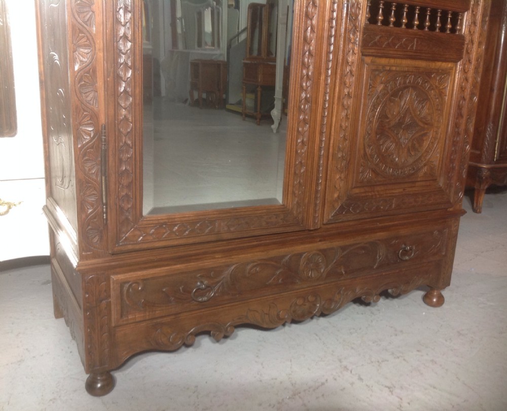 A tall carved walnut Breton armoire featuring one full-length mirrored door and one timber door with detailed relief carving and a spindle gallery. View VIII