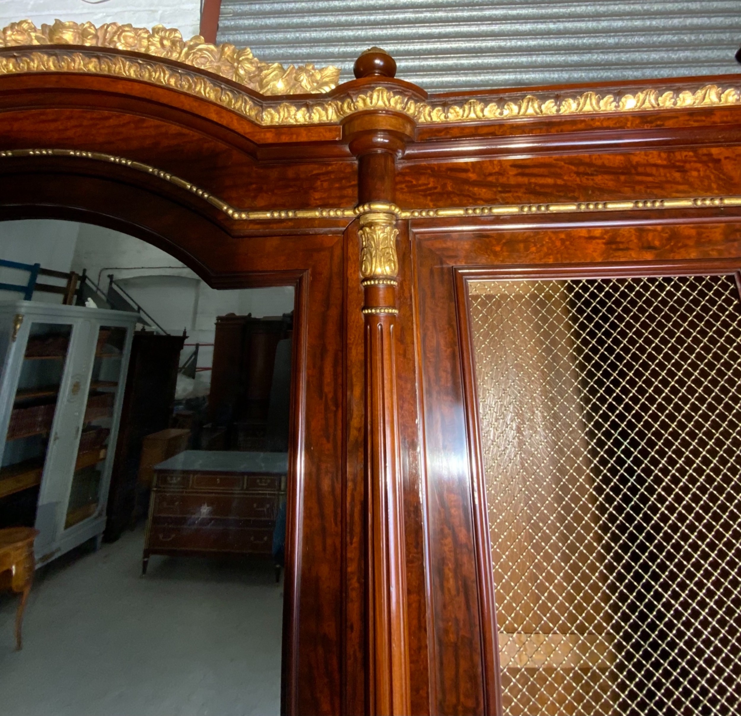 A large mahogany three-door armoire featuring a central arched mirrored door, wire-mesh side panels, and gilt bronze mounts. View III