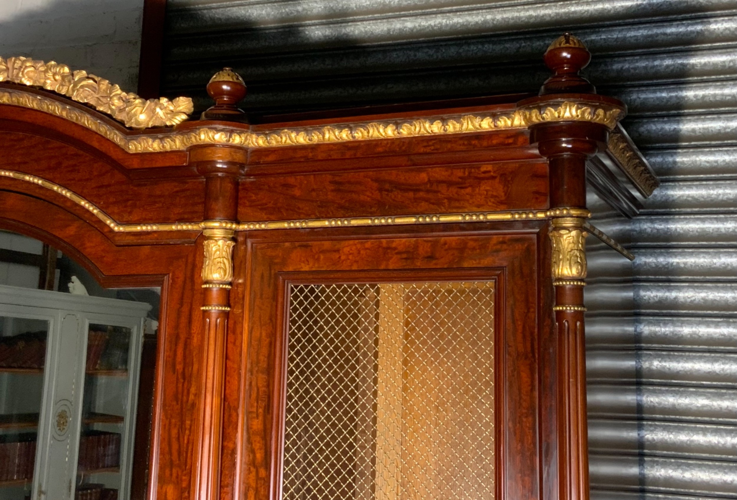 A large mahogany three-door armoire featuring a central arched mirrored door, wire-mesh side panels, and gilt bronze mounts. View V