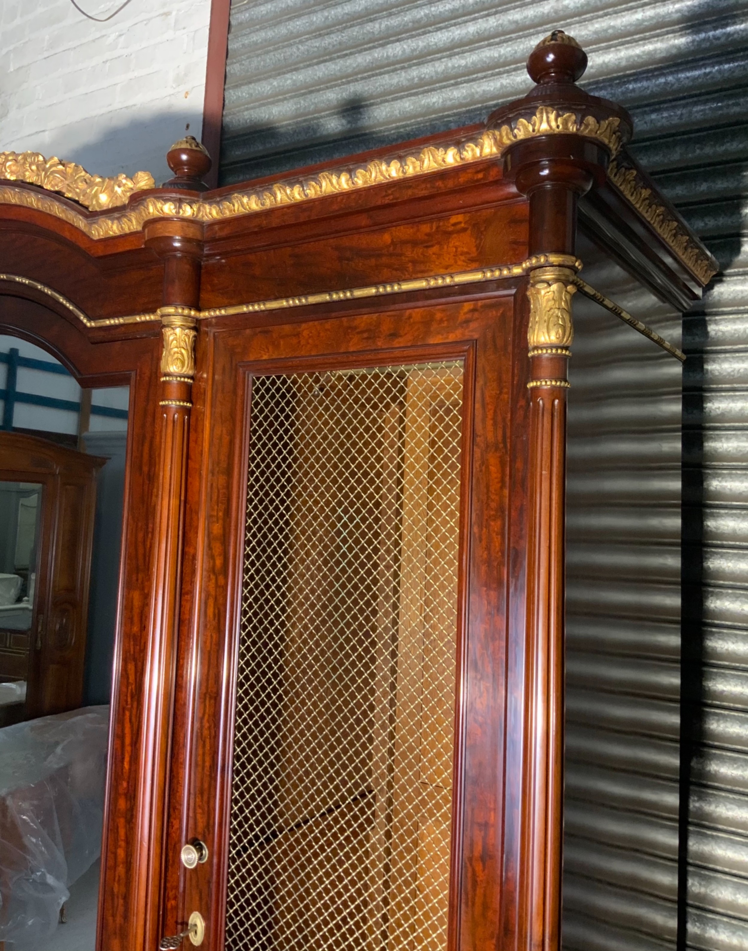 A large mahogany three-door armoire featuring a central arched mirrored door, wire-mesh side panels, and gilt bronze mounts. View VIII