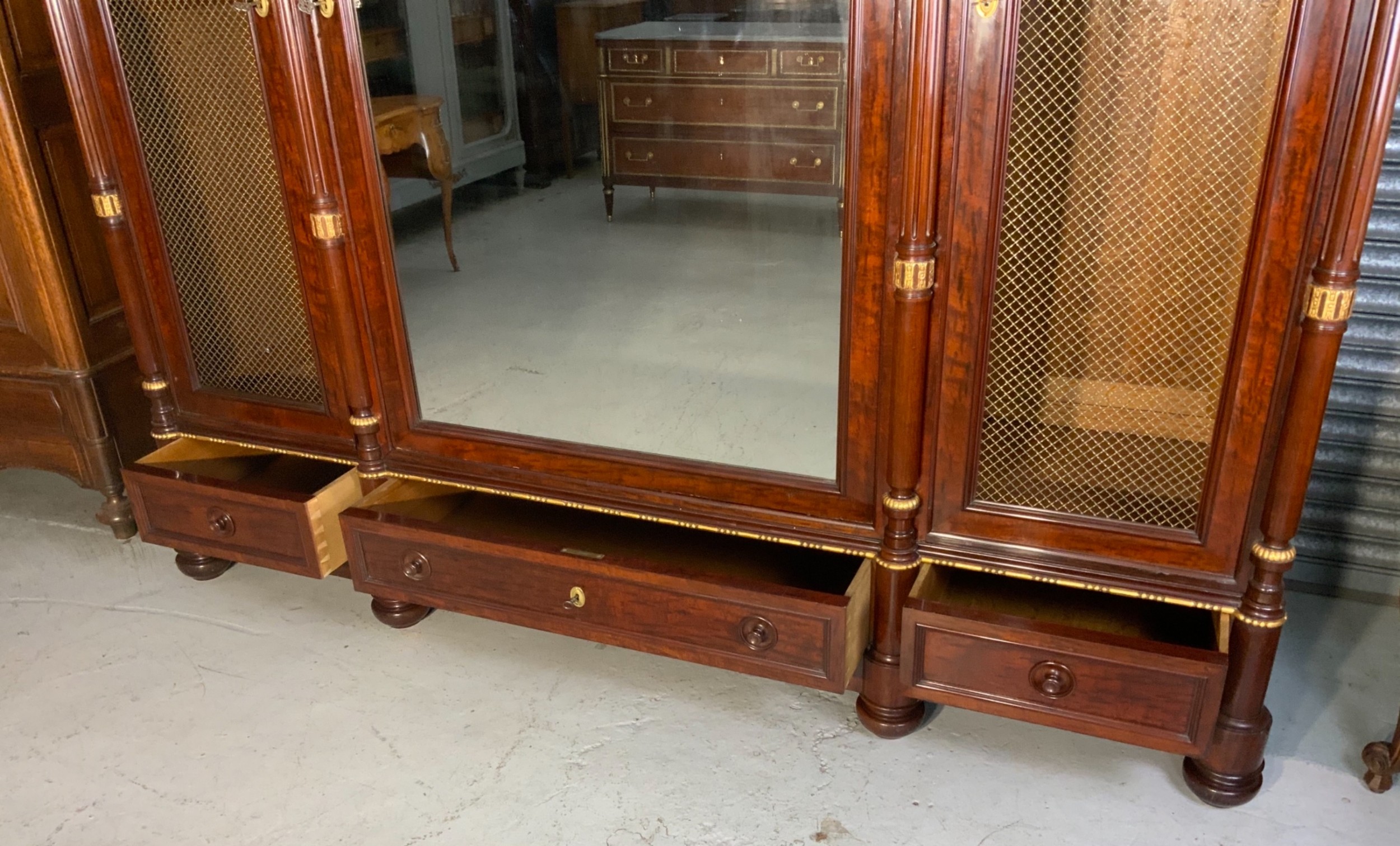 A large mahogany three-door armoire featuring a central arched mirrored door, wire-mesh side panels, and gilt bronze mounts. View XII