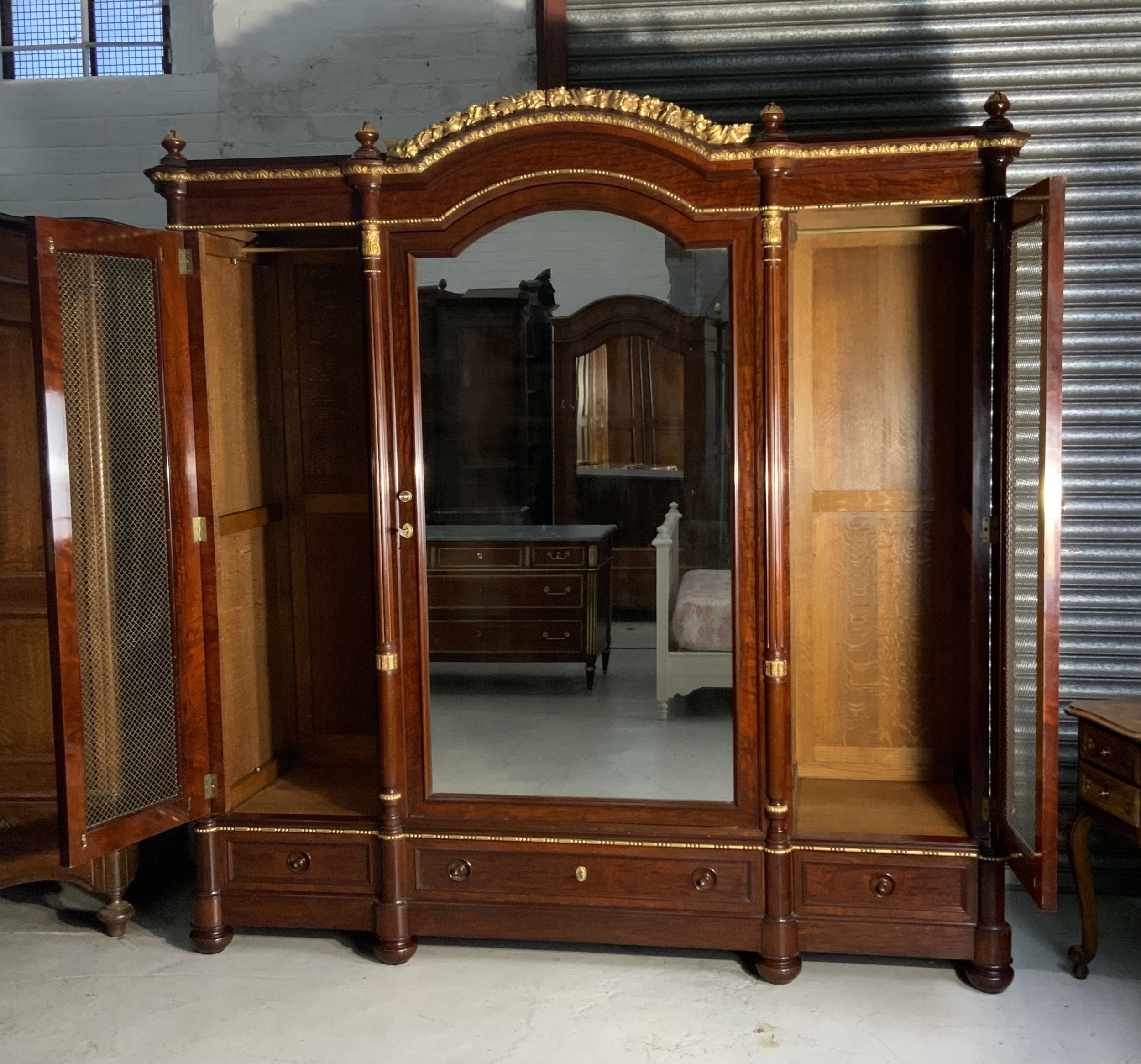 A large mahogany three-door armoire featuring a central arched mirrored door, wire-mesh side panels, and gilt bronze mounts. View XIII