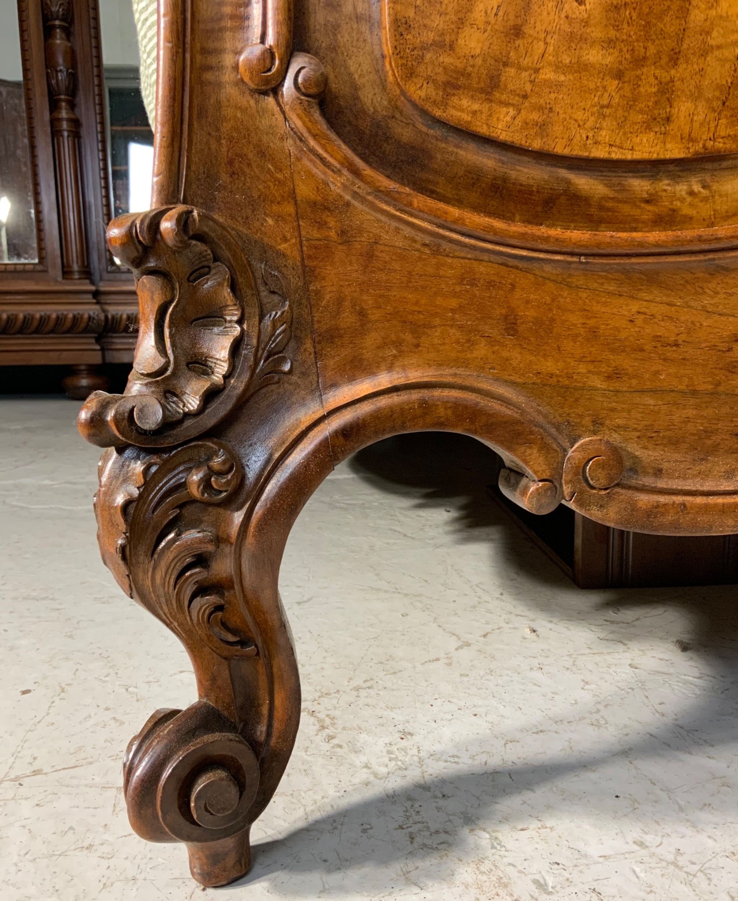 An antique carved walnut bed frame featuring an ornate arched headboard and footboard with carved scrollwork and floral cresting. View II
