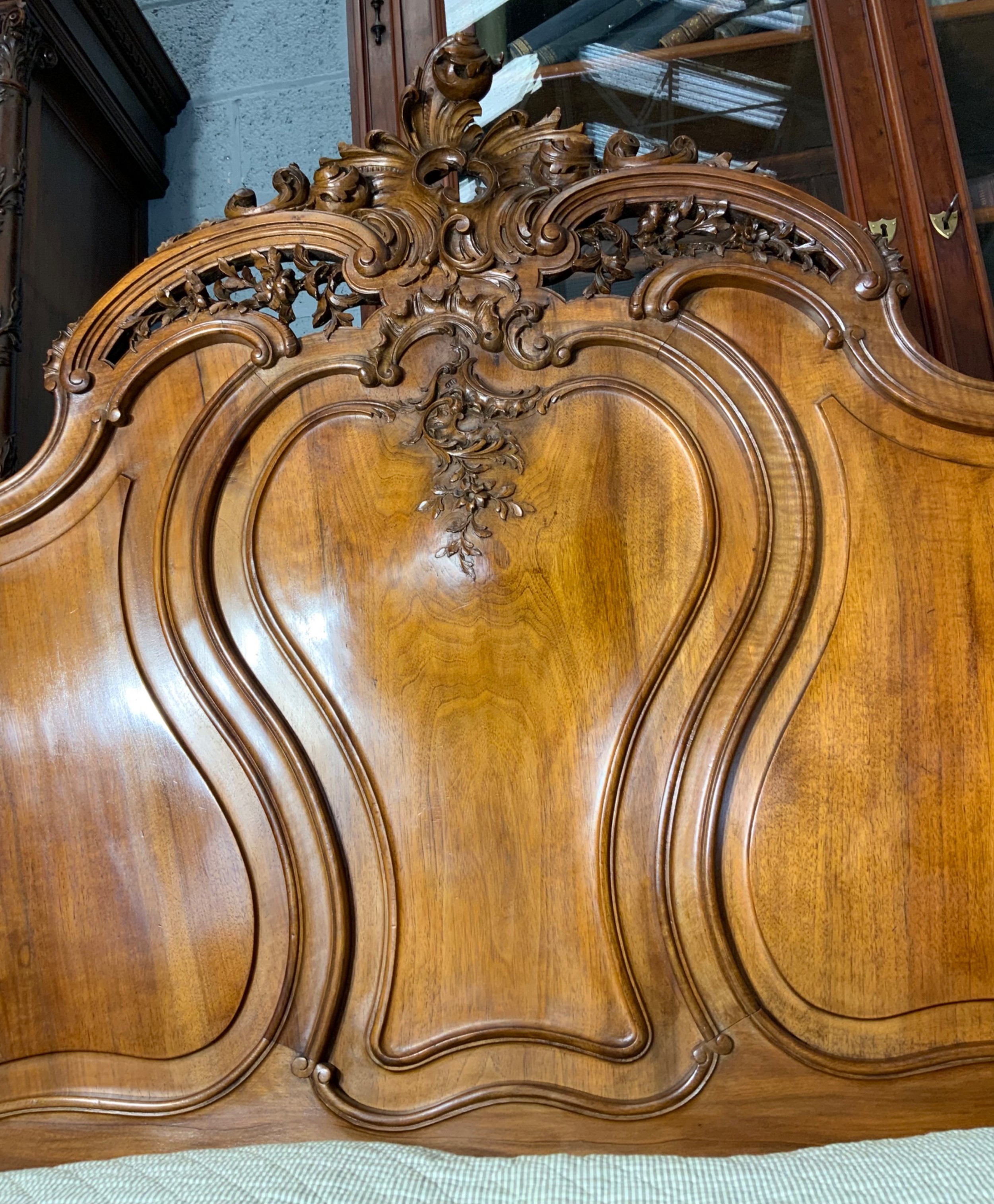An antique carved walnut bed frame featuring an ornate arched headboard and footboard with carved scrollwork and floral cresting. View VI
