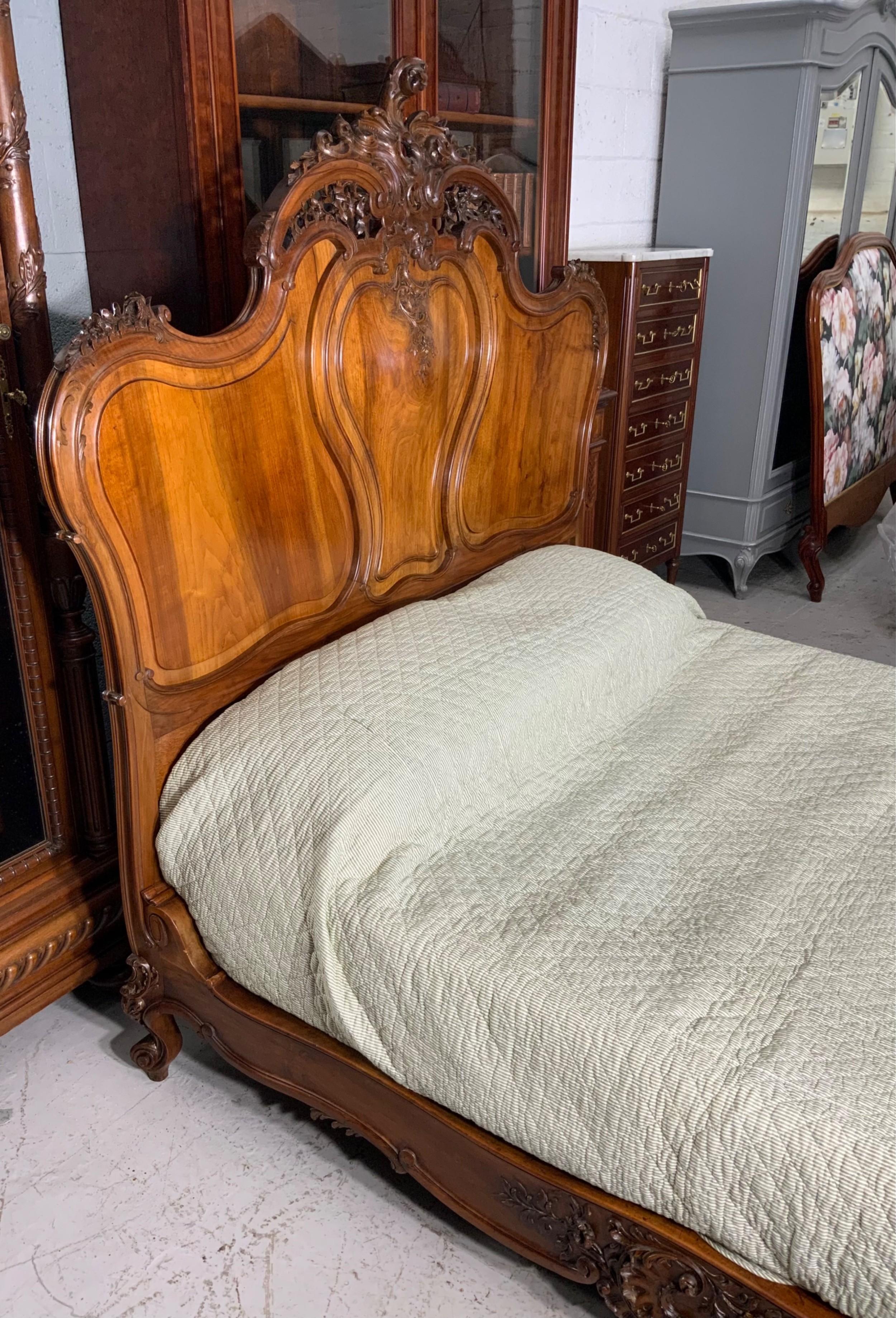 An antique carved walnut bed frame featuring an ornate arched headboard and footboard with carved scrollwork and floral cresting. View IX