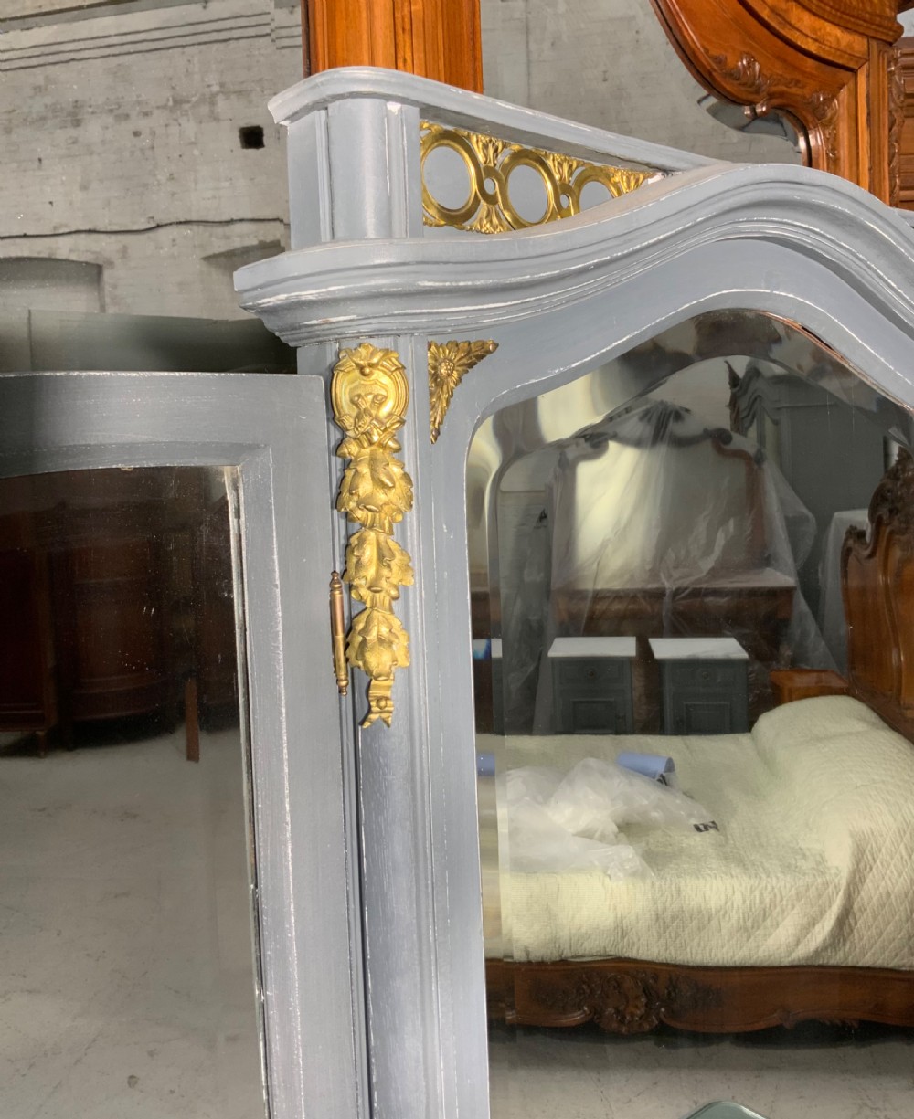 A plummet grey painted French dressing table featuring a central tri-fold mirror, brass embellishments, a glass top, multiple drawers, and turned legs. View V