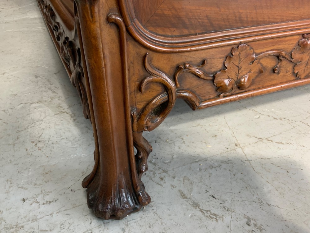 Carved walnut French bed frame with an arched headboard, ornate floral footboard carving, and a pair of matching wooden bedside cabinets. View IX