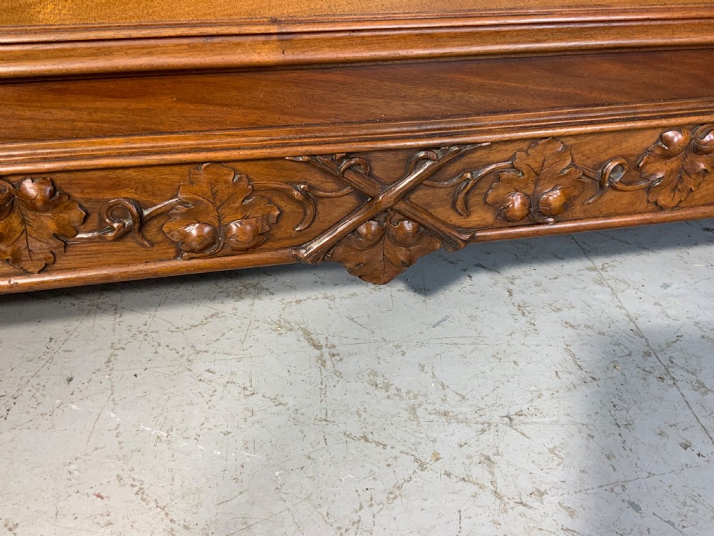 Carved walnut French bed frame with an arched headboard, ornate floral footboard carving, and a pair of matching wooden bedside cabinets. View XXI